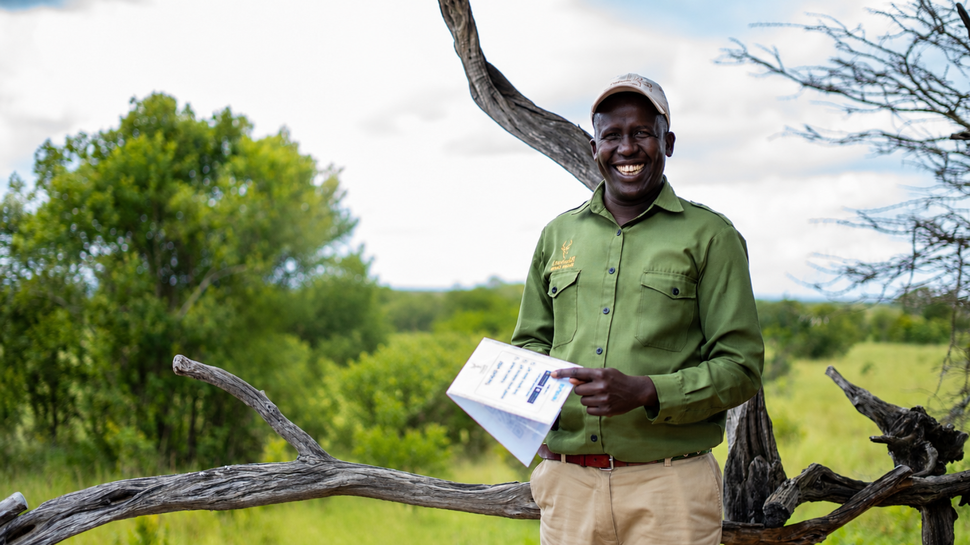 Smiling safari tour guide holding a Shukran QR code card